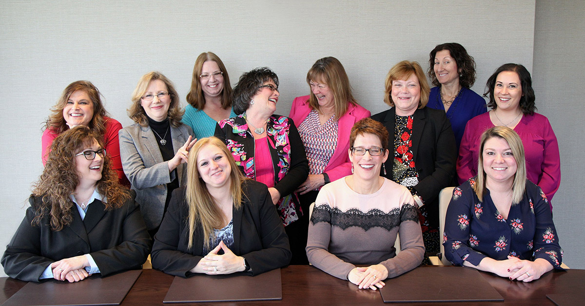 A group of women laughing and smiling around a desk